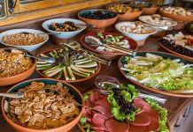 Açık büfe anlayışı aslında yüzyıllar öncesine dayanan bir paylaşım kültürünün modern yansımasıdır. İnsanlar topluluk halinde yemek yerken, farklı seçenekler sunma geleneği tarih boyunca birçok toplumda görülmüştür. Özellikle Osmanlı’da ziyafet sofraları, Avrupa’da ise şölenler bu anlayışın temellerini oluşturmuştur. Günümüzde ise otellerden restoranlara, davetlerden kutlamalara kadar pek çok alanda açık büfe yaygın olarak tercih edilmektedir. Konulu bir haber görseli.