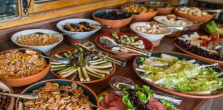 Açık büfe anlayışı aslında yüzyıllar öncesine dayanan bir paylaşım kültürünün modern yansımasıdır. İnsanlar topluluk halinde yemek yerken, farklı seçenekler sunma geleneği tarih boyunca birçok toplumda görülmüştür. Özellikle Osmanlı’da ziyafet sofraları, Avrupa’da ise şölenler bu anlayışın temellerini oluşturmuştur. Günümüzde ise otellerden restoranlara, davetlerden kutlamalara kadar pek çok alanda açık büfe yaygın olarak tercih edilmektedir. Konulu bir haber görseli.