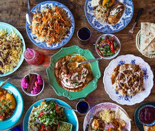 Afganistan, tarih boyunca farklı medeniyetlerin kesişim noktası olmuş bir coğrafyada yer alır ve bu durum mutfağına doğrudan yansımıştır. Afganistan mutfağı, Orta Asya, İran ve Hint kültürlerinin etkisiyle şekillenmiş, hem lezzet hem de çeşitlilik açısından zengin bir gelenek sunar. Bu mutfak, özellikle pirinç, et ve baklagillerin ustaca kullanımı ile bilinir. Binlerce yıllık bir tarih, Afgan yemek kültürünün bugünkü karakterini oluşturmuş ve hem günlük hem de özel günlerde sofralara aktarılmıştır. Konulu bir haber görseli.