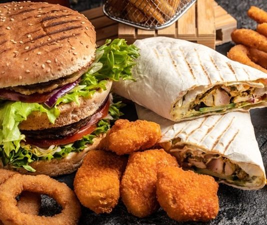 Dünya genelinde hızla yaygınlaşan fastfood kültürü, modern yaşam tarzının en dikkat çeken alışkanlıklarından biri haline geldi. Özellikle 20. yüzyılın ikinci yarısından itibaren Amerika’da doğup tüm dünyaya yayılan bu kültür, kısa sürede milyonlarca insanın günlük hayatına yerleşti. Hızlı, pratik ve görece ucuz olması nedeniyle tercih edilen fastfood, insanların yoğun iş temposu ve zaman sıkıntısı yaşadığı modern şehir yaşamında büyük bir kolaylık sağladı. Konulu bir haber görseli.