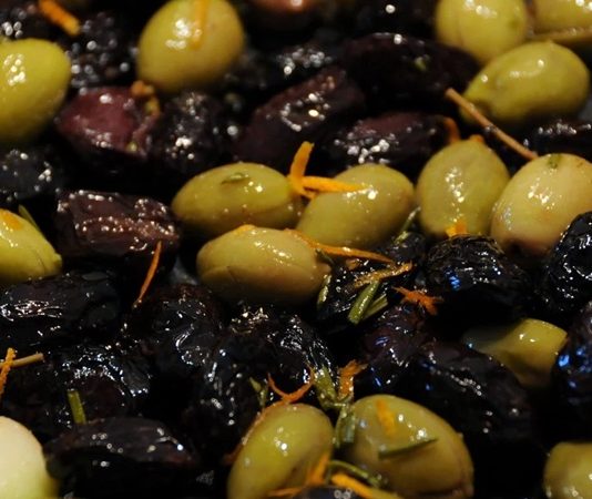 Sofralarda Zeytin Çeşitleri Ve Lezzet Dünyası Zeytin, Akdeniz mutfağının en önemli ve en eski besinlerinden biri olarak sofralarda vazgeçilmez bir yer tutar. Hem sofralık olarak hem de zeytinyağı yapımında kullanılan zeytin, çeşitliliğiyle de dikkat çeker. Türkiye’de özellikle Ege, Marmara ve Akdeniz bölgelerinde yetişen birçok zeytin türü bulunur. Sofralarda zeytin çeşitleri, farklı tat ve aromalarıyla hem damak tadını zenginleştirir hem de kültürel bir miras olarak nesilden nesile aktarılır. Konulu bir haber görseli.