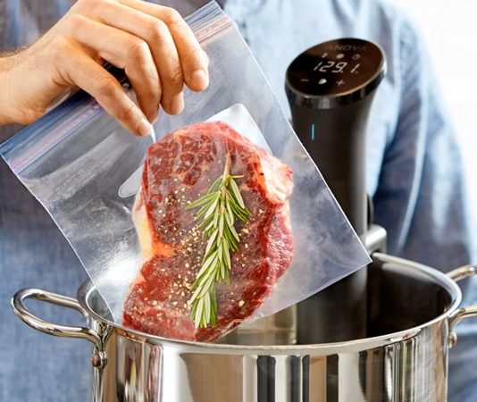 Sous vide Fransızca’da “vakum altında” anlamına gelen bir pişirme tekniğidir. Yiyecekler özel poşetlerin içine yerleştirilip vakumlanır ve ardından kontrollü bir şekilde düşük sıcaklıkta su banyosunda pişirilir. Bu yöntem 1970’li yıllarda profesyonel şefler tarafından keşfedilmiş ve zamanla restoran mutfaklarından ev mutfaklarına kadar yayılmıştır. Özellikle et, balık ve sebzelerde istenen pişirme derecesine ulaşmayı kolaylaştırdığı için tercih edilmektedir. Konulu bir haber görseli.