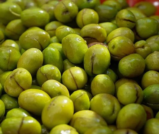 Akdeniz’in bereketli topraklarında yetişen yeşil zeytin, binlerce yıllık bir geçmişe sahip. Tarih boyunca birçok uygarlık için hem besin kaynağı hem de kültürel bir sembol olmuştur. Antik dönemlerde kutsal sayılan zeytin ağacı, barışın ve bolluğun işareti olarak görülmüş, sofralara sunduğu yeşil zeytin ile insanlığın yaşamına değer katmıştır. Konulu bir haber görseli.