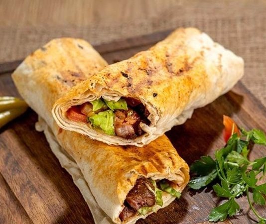 Dürüm, Türk mutfağının en popüler sokak lezzetlerinden biri olarak bilinir. Genellikle lavaş veya yufka ekmeği içinde sunulan bu hızlı atıştırmalık, hem doyurucu hem de pratik bir yemek seçeneği oluşturur. Tarih boyunca Orta Doğu mutfağı ile etkileşim içinde olan dürüm, zamanla Türkiye’de kendine özgü bir biçim kazanmıştır. Konulu bir haber görseli.