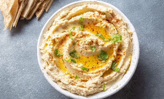 Humus, Orta Doğu mutfağının en bilinen ve sevilen mezelerinden biridir. Başlıca malzemeleri nohut, tahin, limon suyu, sarımsak ve zeytinyağı olan bu özel tarif, yüzyıllardır sofralarda yerini almaktadır. Tarihi çok eski dönemlere dayanan humus, özellikle Lübnan, Suriye, Filistin ve Türkiye gibi bölgelerde yaygın olarak tüketilir. Bugün ise dünya genelinde sağlıklı bir atıştırmalık ya da ana yemek yanında tamamlayıcı olarak tercih edilmektedir. Konulu bir haber görseli.