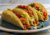 Taco, Meksika mutfağının en bilinen ve sevilen sokak lezzetlerinden biridir. Mısır veya buğday bazlı tortilla içine çeşitli malzemelerin doldurulmasıyla hazırlanır. Tarihi, yüzyıllar öncesine dayanan taco, Meksika halkının günlük beslenmesinde önemli bir yere sahiptir. Konulu bir haber görseli.