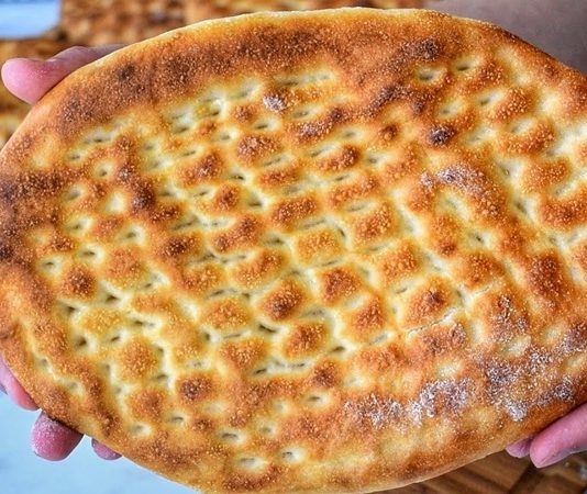 Tırnak Pide: Gelenekten Günümüze Uzanan Lezzet Türk mutfağının en sevilen ekmek çeşitlerinden biri olan tırnak pide, özellikle Ramazan sofralarının ve kebapçıların vazgeçilmez lezzetleri arasında yer alır. Yumuşak içi ve hafif çıtır kabuğu ile öne çıkan bu pide, hem sade olarak hem de farklı yemeklerin eşlikçisi şeklinde tüketilir. Tırnak pide, adını hamura parmak uçlarıyla yapılan tırnak izlerinden alır ve bu izler pişirme sırasında pideye özgün bir görünüm kazandırır. Hem görselliği hem de tadıyla sofraları süsleyen bu geleneksel lezzet, Anadolu’nun mutfak kültüründe önemli bir yere sahiptir. Konulu bir haber görseli.