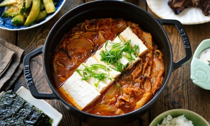 Kimchi Jjigae Kore Mutfağının Baharatlı ve Sağlıklı Çorbası Globalleşiyor Güney Kore mutfağının en ikonik çorbalarından biri olan Kimchi Jjigae, son yıllarda dünya genelinde hem restoran menülerinde hem de ev yapımı tariflerde popülerliğini artırıyor. Özellikle fermente lahana, baharatlı biber ve dengeli et suyu ile hazırlanan bu çorba, hem doyurucu hem de sağlık açısından zengin bir yemek olarak öne çıkıyor. Türkiye’de de gastronomi meraklılarının ilgisini çeken Kimchi Jjigae, Kore mutfağının globalleşmesinde önemli bir rol oynuyor. Lezzeti ve besleyici özellikleri sayesinde çorba severler için hem geleneksel hem de modern alternatifler sunuyor. Konulu bir haber görseli.