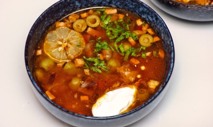 Solyanka, Doğu Avrupa’nın köklü mutfak kültürünü yansıtan, aroması yoğun, baharatı dengeli ve malzemeleri çeşitlilik gösteren özel bir çorbadır. Tarihi Rusya, Ukrayna ve Belarus gibi ülkelerin geleneksel sofralarına kadar uzanan bu yemek, yıllar içinde farklı şekillerde yorumlanmış ve her bölgede kendine özgü bir tat kazanmıştır. Günümüzde dünya gastronomisinde yeniden yükselen ilgi sayesinde solyanka, yalnızca bir çorba olmanın ötesine geçerek kültürel bir temsil niteliği taşımaya başlamıştır. Özellikle güçlü ekşi-aromalı yapısı ve doyurucu özelliği, onu diğer çorbalardan ayıran temel faktörler arasında yer alır. Konulu bir haber görseli.