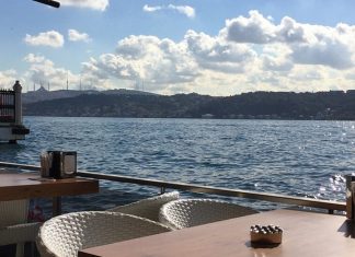 Denizle İç İçe Yaşamın Vazgeçilmezi Sahil Kafeleri Şehir hayatının yoğun temposu içinde denizle temas edilebilen nadir alanlardan biri olan sahil kafeleri, son yıllarda hem yerel halkın hem de ziyaretçilerin en çok tercih ettiği mekânlar arasında yer alıyor. Denizin sesi, açık hava ferahlığı ve manzara eşliğinde sunulan yeme içme deneyimi, sahil kafelerini sıradan kafelerden ayıran en önemli unsur olarak öne çıkıyor. Bu mekânlar, sadece bir şeyler içilen alanlar değil; aynı zamanda şehirden kaçışın en kolay yollarından biri hâline geliyor. Konulu bir haber görseli.