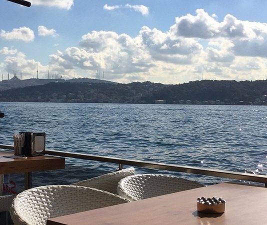 Şehir hayatının yoğun temposu içinde denizle temas edilebilen nadir alanlardan biri olan sahil kafeleri, son yıllarda hem yerel halkın hem de ziyaretçilerin en çok tercih ettiği mekânlar arasında yer alıyor. Denizin sesi, açık hava ferahlığı ve manzara eşliğinde sunulan yeme içme deneyimi, sahil kafelerini sıradan kafelerden ayıran en önemli unsur olarak öne çıkıyor. Bu mekânlar, sadece bir şeyler içilen alanlar değil; aynı zamanda şehirden kaçışın en kolay yollarından biri hâline geliyor. Konulu bir haber görseli.